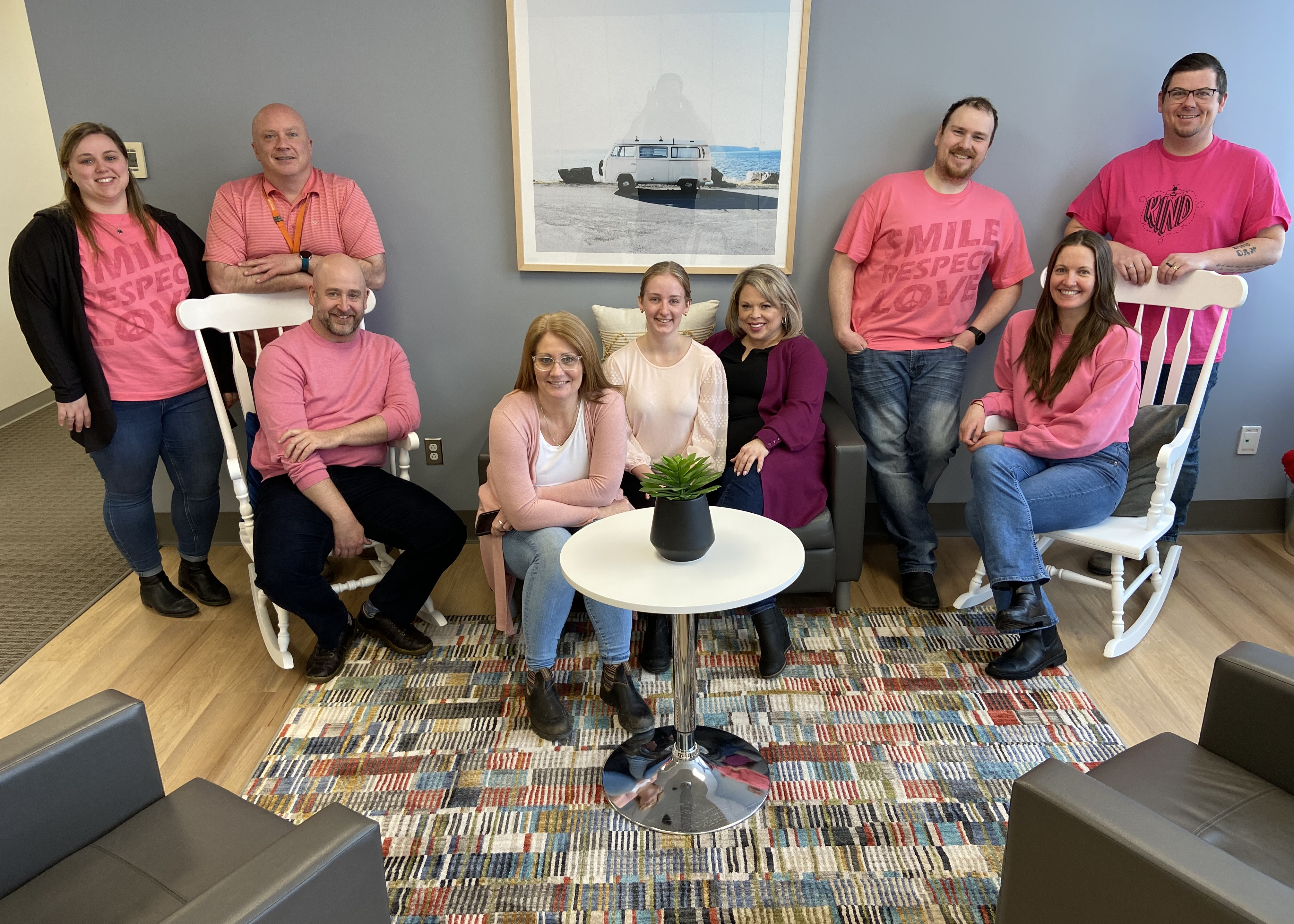 Our team sits together smiling for the camera in pink shirts.
