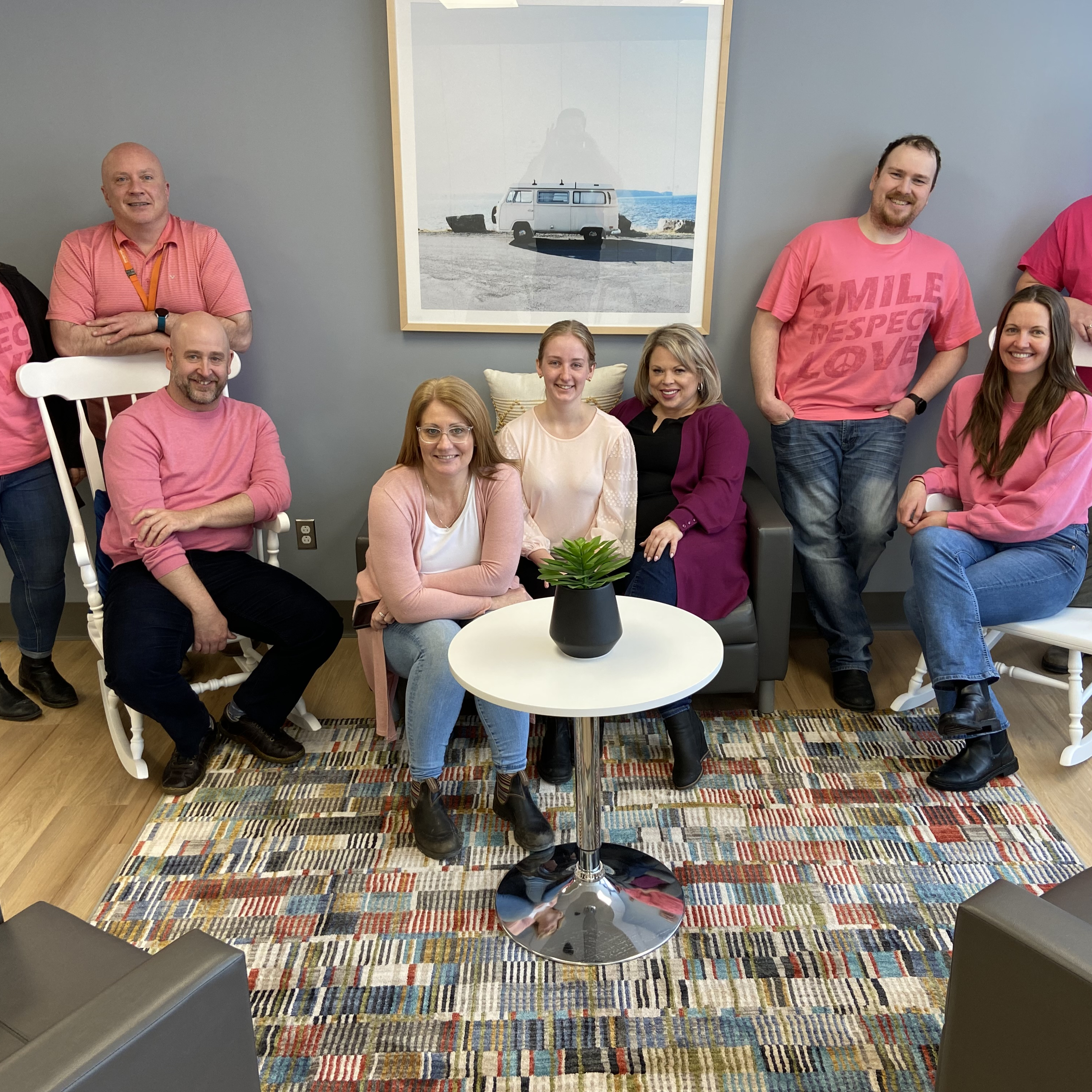Our team sits together smiling for the camera in pink shirts.